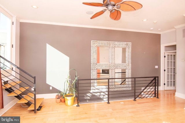 interior space with an upstairs landing, wood finished floors, baseboards, and ornamental molding