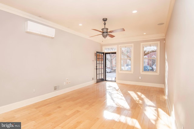 spare room featuring crown molding, baseboards, light wood finished floors, and a wall mounted AC