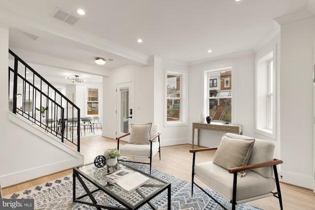 living area featuring light wood-style floors, stairs, and crown molding