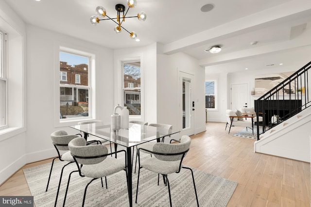 dining space with a notable chandelier, light wood-style flooring, stairway, and baseboards