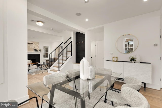 dining space with baseboards, recessed lighting, a fireplace, stairs, and light wood-style floors