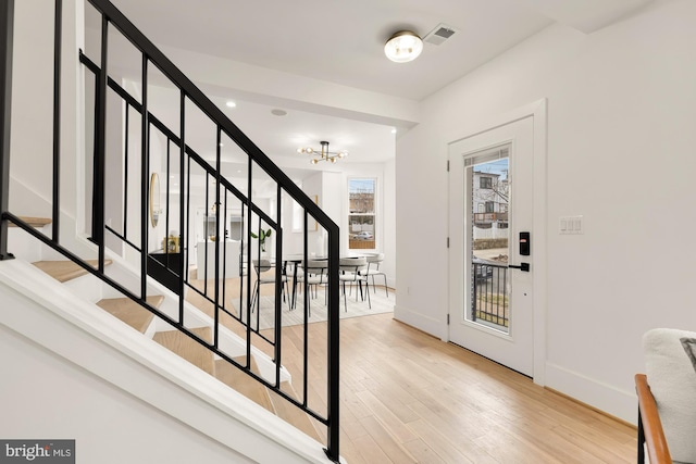 foyer featuring stairway, baseboards, light wood-style flooring, and a chandelier