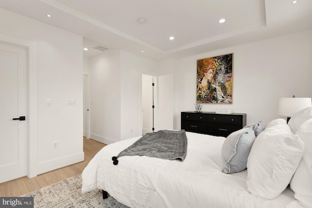 bedroom with visible vents, baseboards, a tray ceiling, recessed lighting, and light wood-style flooring