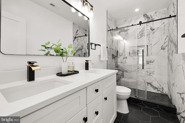 bathroom with a marble finish shower, double vanity, toilet, and a sink