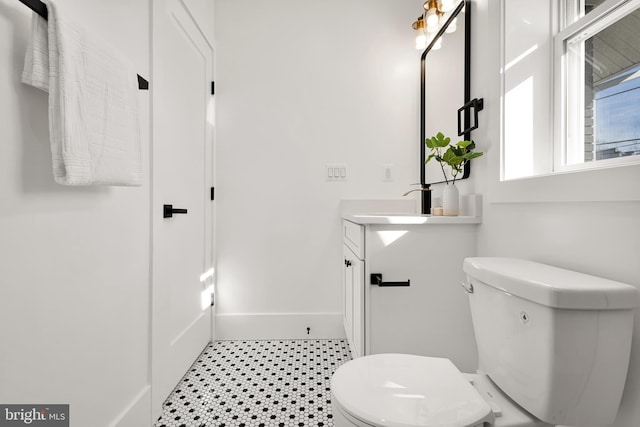 bathroom featuring toilet, vanity, and baseboards