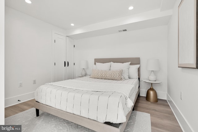 bedroom with recessed lighting, wood finished floors, visible vents, and baseboards