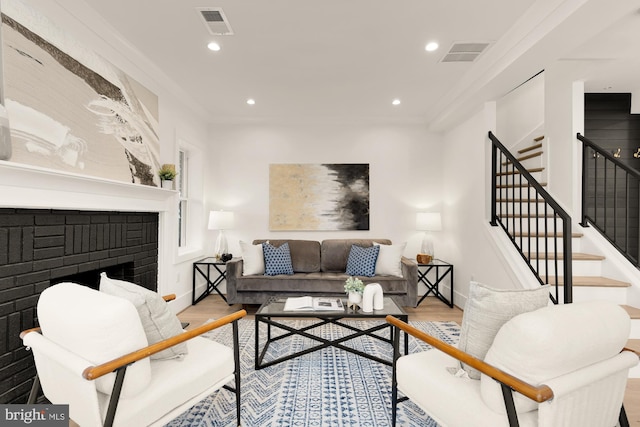 living area with visible vents, wood finished floors, a fireplace, and stairway