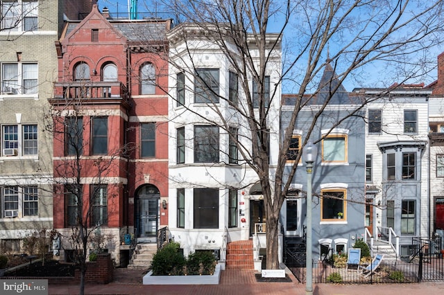 townhome / multi-family property with a fenced front yard and brick siding