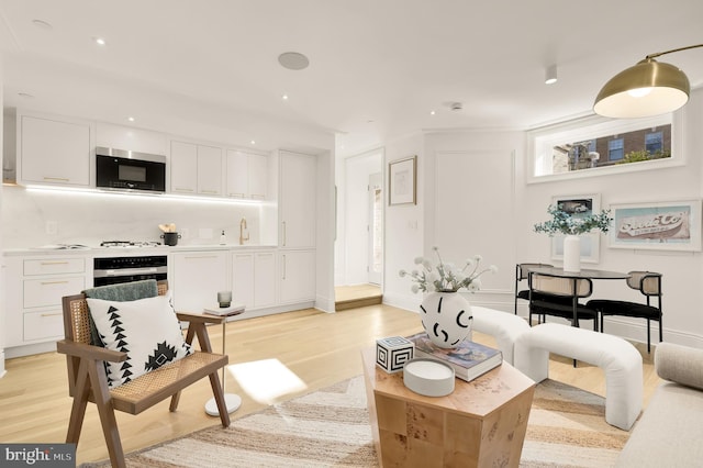 living area with recessed lighting, light wood-style flooring, and baseboards