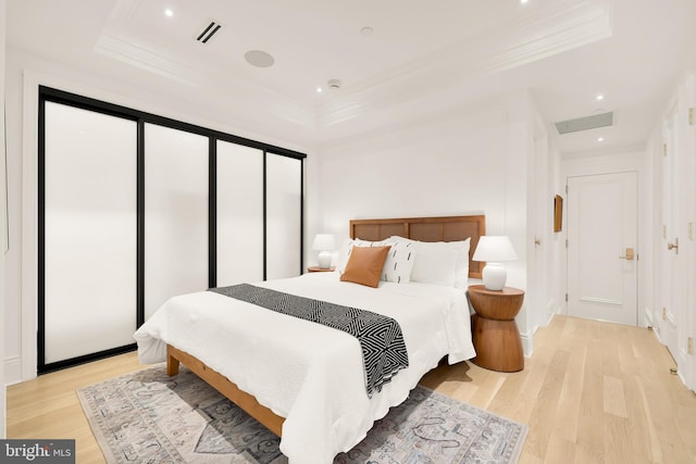 bedroom with visible vents, light wood finished floors, and ornamental molding