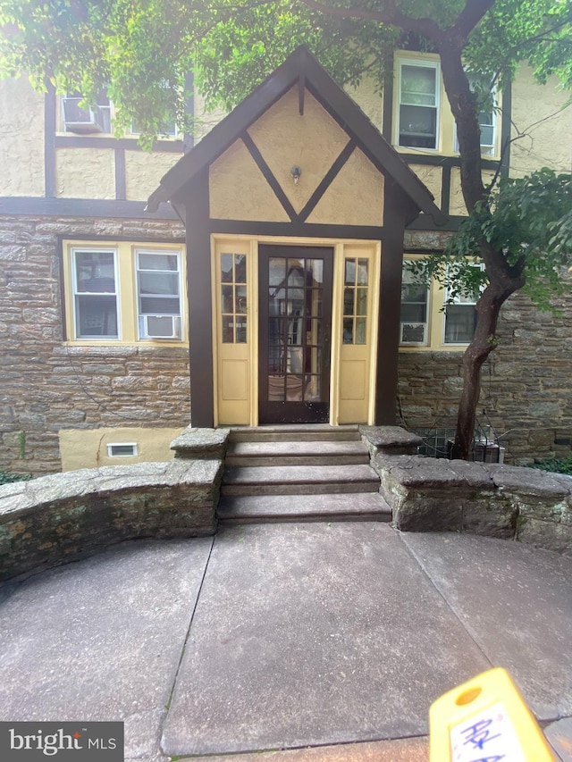 property entrance with stucco siding and stone siding