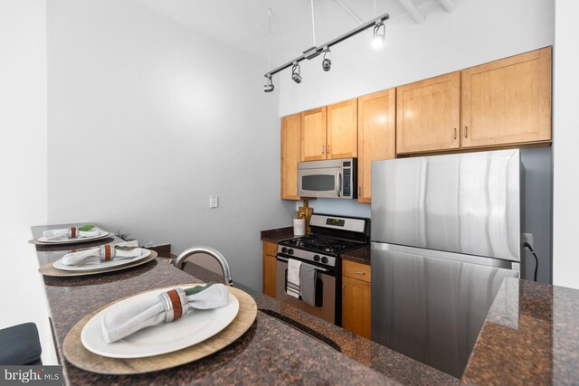 kitchen with track lighting, dark stone countertops, and appliances with stainless steel finishes