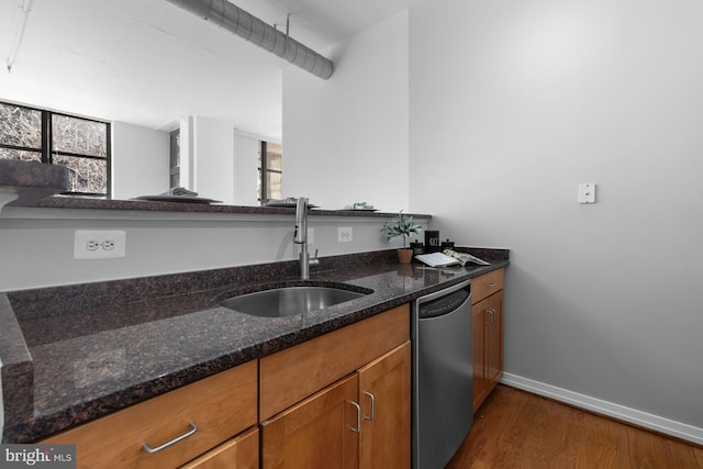 kitchen with baseboards, dark wood-style flooring, a sink, stainless steel dishwasher, and brown cabinets