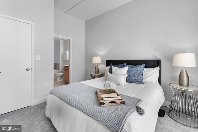 carpeted bedroom featuring ensuite bath and baseboards