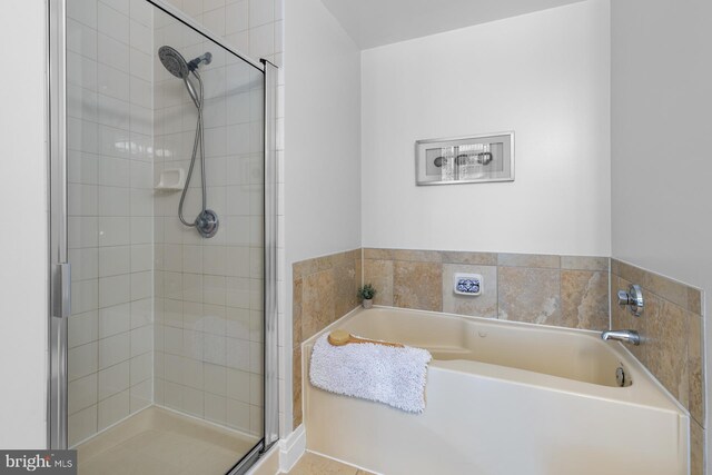 full bathroom featuring a shower stall and a garden tub