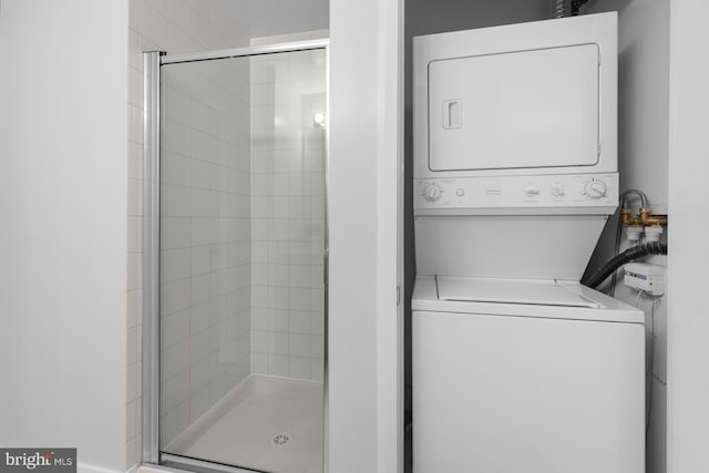 clothes washing area featuring stacked washer and clothes dryer and laundry area