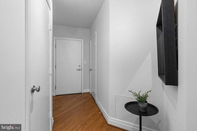 corridor featuring baseboards and light wood-style flooring