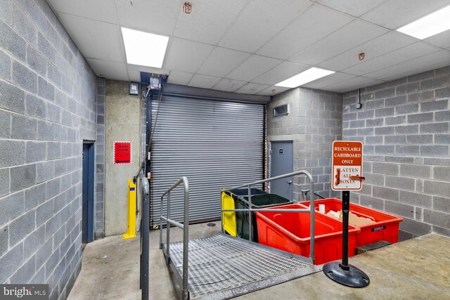 interior space featuring a drop ceiling, concrete block wall, and concrete floors