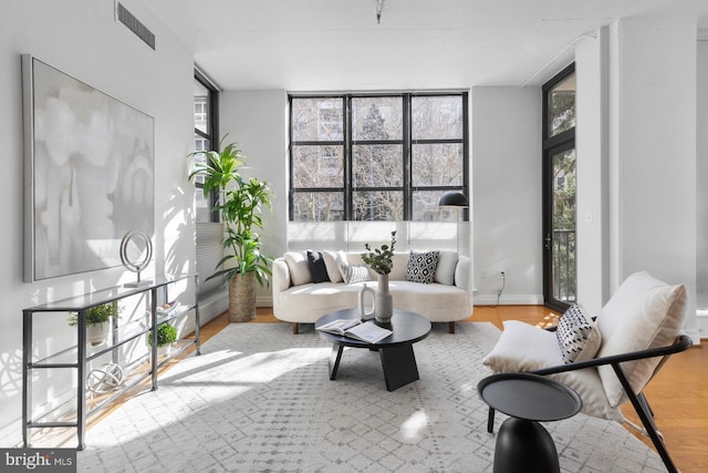 living room featuring visible vents, wood finished floors, baseboards, and expansive windows