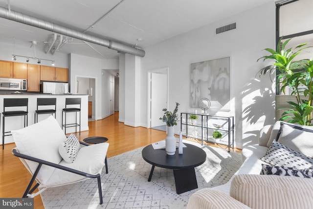 living area featuring visible vents, baseboards, track lighting, and light wood finished floors