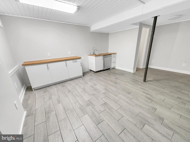 finished basement featuring light wood-style floors, baseboards, and a sink