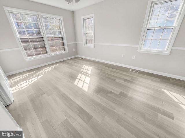 spare room featuring visible vents, light wood-style flooring, baseboards, and ceiling fan