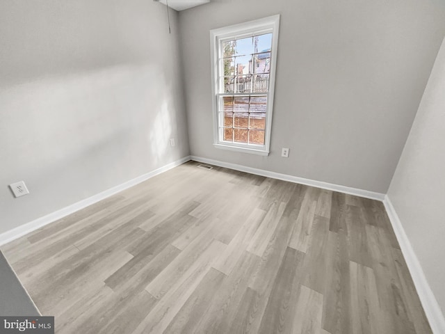 unfurnished room featuring visible vents, baseboards, and wood finished floors