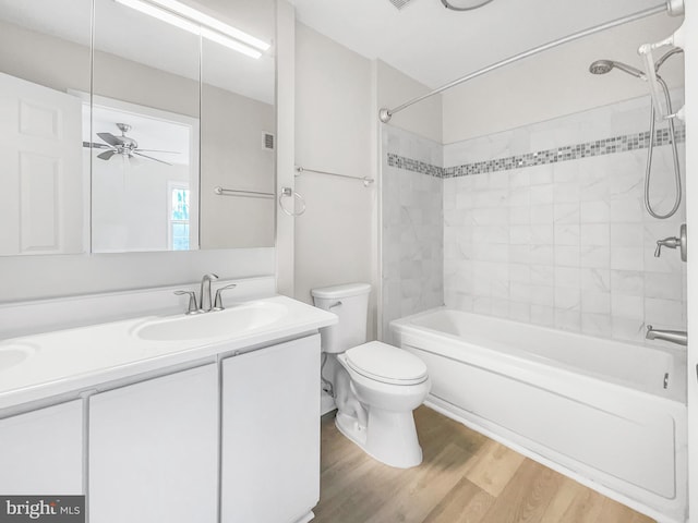 bathroom featuring toilet, a ceiling fan, wood finished floors,  shower combination, and vanity