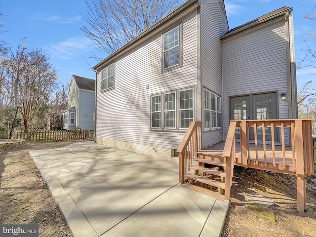 rear view of property featuring a wooden deck, a patio, and fence