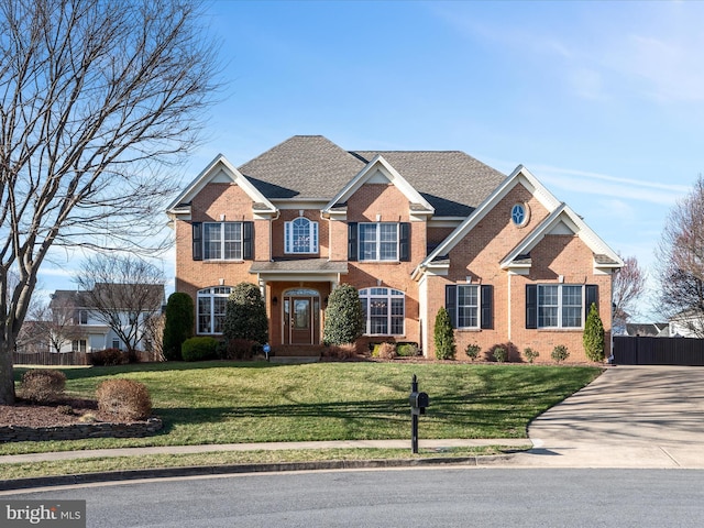 view of front of property featuring brick siding, driveway, a front lawn, and fence