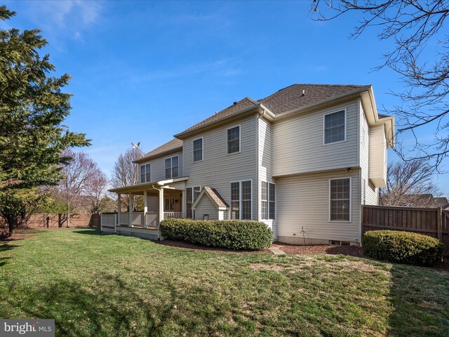 back of property featuring a lawn and fence