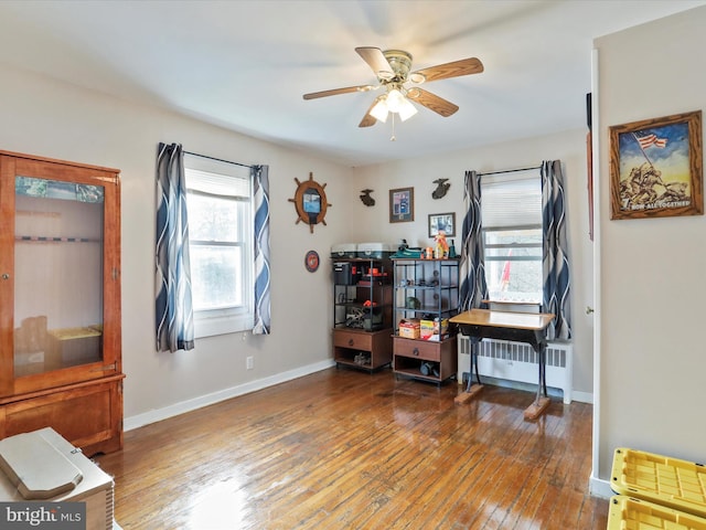 miscellaneous room featuring baseboards, wood-type flooring, ceiling fan, and radiator heating unit