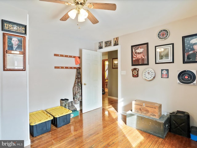 interior space featuring baseboards, hardwood / wood-style floors, and a ceiling fan