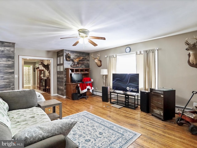 living room with ceiling fan, a baseboard radiator, baseboards, and wood finished floors