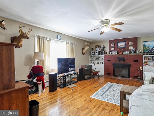 living area featuring ceiling fan, wood finished floors, and a fireplace