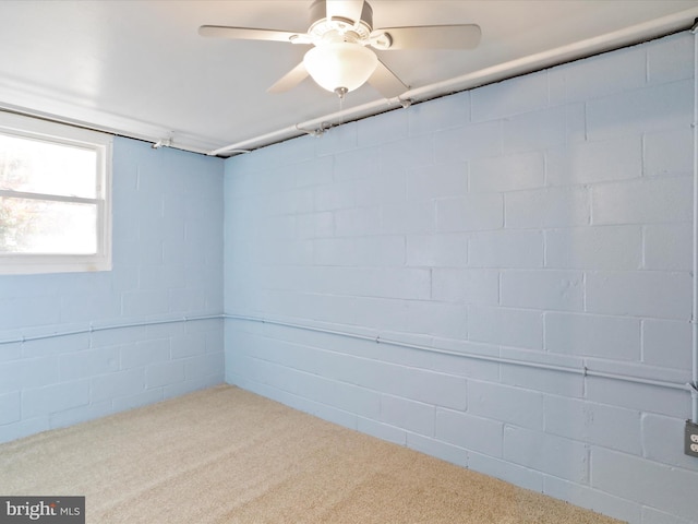 basement featuring carpet flooring, concrete block wall, and a ceiling fan