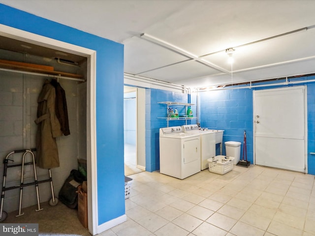 clothes washing area with concrete block wall, laundry area, and washer and clothes dryer