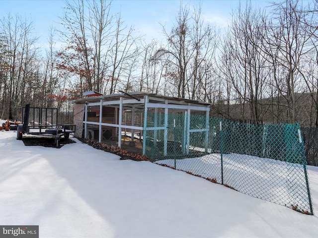 snow covered rear of property with an outdoor structure, a trampoline, fence, and exterior structure