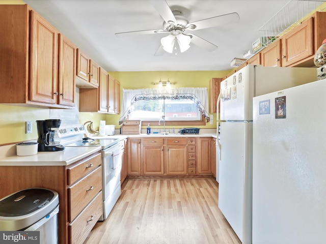 kitchen with light countertops, light wood-style flooring, white appliances, a ceiling fan, and a sink