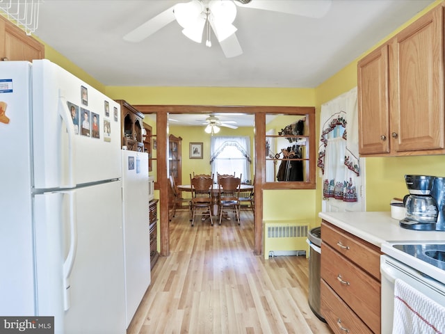 kitchen with radiator, a ceiling fan, light wood finished floors, freestanding refrigerator, and light countertops