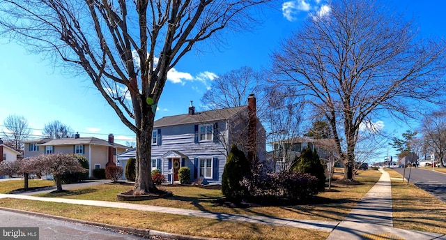 view of front of house with a front lawn, a residential view, and a chimney