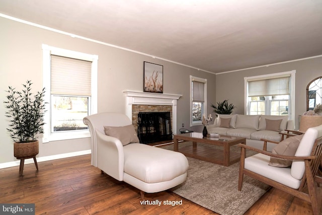 living room with baseboards, a fireplace, wood finished floors, and crown molding