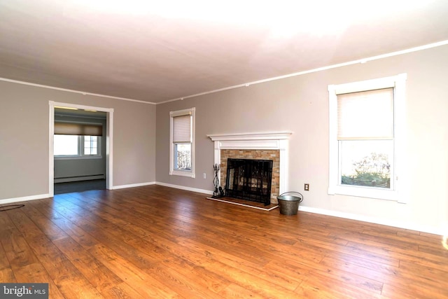 unfurnished living room with a fireplace with raised hearth, baseboards, ornamental molding, hardwood / wood-style floors, and a baseboard radiator