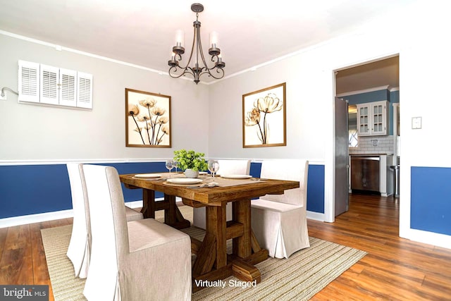 dining room with a notable chandelier, wood finished floors, and ornamental molding