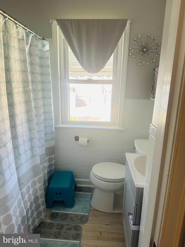 bathroom featuring toilet, curtained shower, wood finished floors, tile walls, and vanity