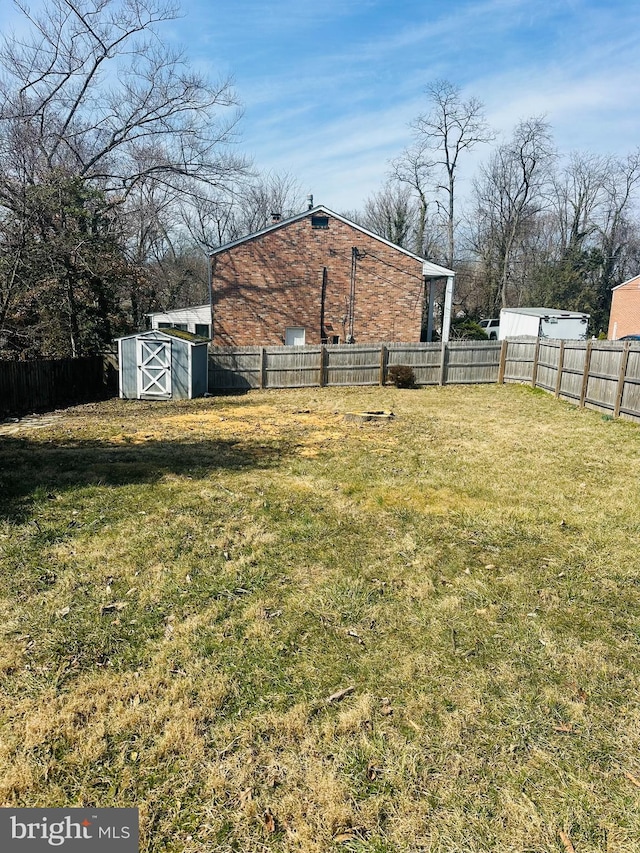 view of yard with a storage shed, a fenced backyard, and an outdoor structure