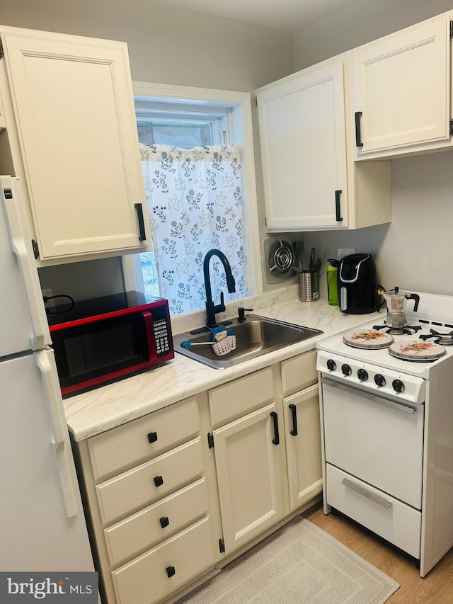 kitchen featuring light wood finished floors, white cabinets, white electric range, and a sink