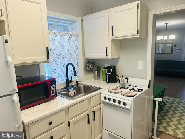 kitchen featuring white appliances, white cabinets, light countertops, and a sink