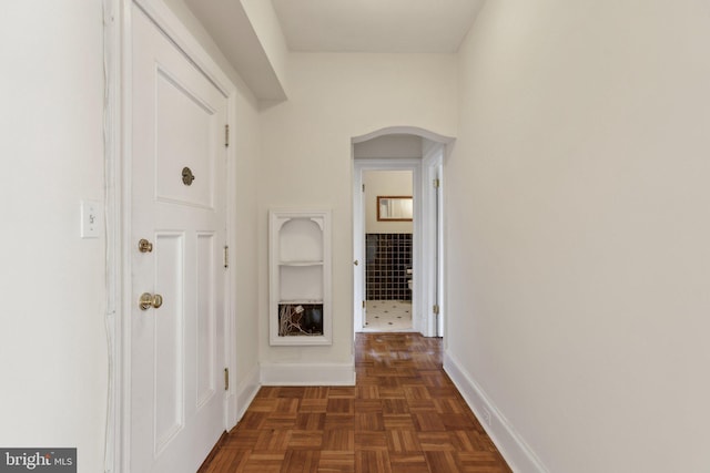 hallway with baseboards and arched walkways