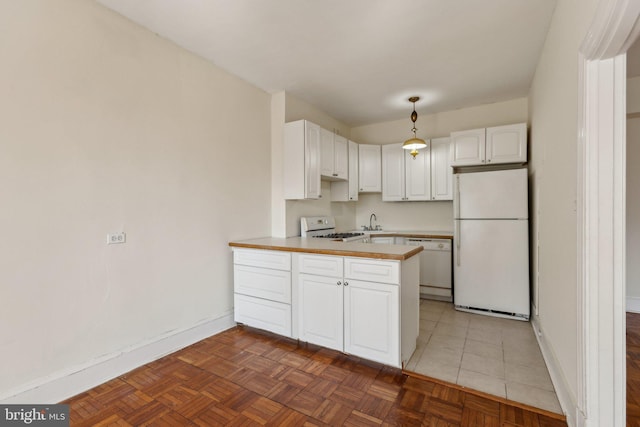 kitchen featuring light countertops, a peninsula, white cabinets, white appliances, and a sink